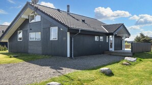 Moderni, kaksikerroksinen talo, jossa on kalteva katto, satelliittiantenni ja savupiippu.