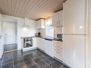 A modern kitchen with white cabinets, a stainless steel oven, a microwave, and a refrigerator. - 4 Star Holiday Home in Norre Nebel (Norre Nebel)