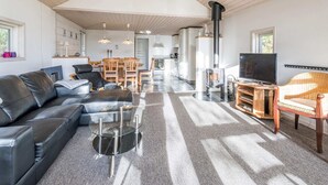 Ein modernes Wohnzimmer mit einer schwarzen Ledersofa, einem Glastisch, einer Holz-TV-Kommode und einem großen Fenster.