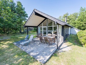 Une maison dotée d’une terrasse, d’un espace salon extérieur et d’un grand porche vitré.