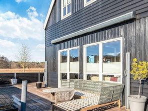 A modern house with a deck, a sofa, and potted plants.