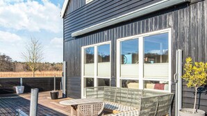 Una casa moderna con terraza, sofá y plantas en macetas.