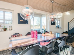 A dining area with a wooden table, black chairs, and clear pendant lights.