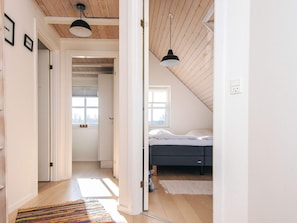 A room with a bed, a window, and a door leading to another room. - Holiday Home in Juelsminde (Juelsminde)