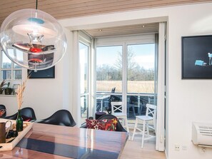 A modern dining area with a large table, chairs, and a unique spherical light fixture. - Holiday Home in Juelsminde (Juelsminde)