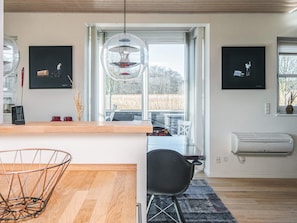 Une cuisine moderne avec un plan de travail en bois, un luminaire suspendu et une vue sur l’extérieur.