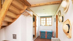 A narrow hallway with a wooden staircase on the left, a radiator on the floor, and a window at the end. - Idyllic Countryside Retreat-by Traum (Rudkobing)
