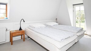 A bedroom with a bed, a bedside table, a lamp, and a window. - Idyllic Countryside Retreat-by Traum (Rudkobing)