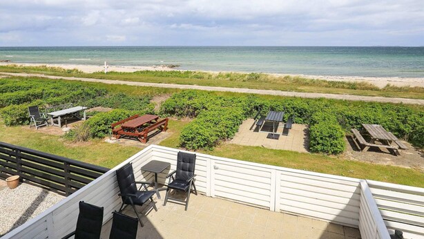 Varanda com vista para a praia, área de estar externa e jardim.