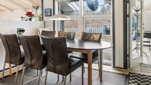 Un comedor con una mesa redonda y sillas, una lámpara colgante y vistas amplias por los ventanales.