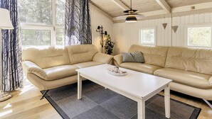 Una sala acogedora con un sofá color beige, una mesa de centro blanca y una lámpara colgante.