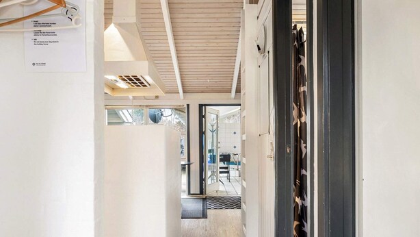 Un pasillo con piso de madera, un respiradero en el techo y una puerta que da a una habitación con vistas.