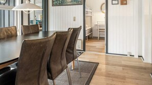 Un comedor con una mesa de madera, sillas marrones y una lámpara colgante.