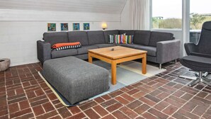 Uma sala de estar moderna com sofá seccional, mesa de centro de madeira e poltrona cinza.
