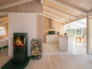 A modern kitchen with a central island, a fireplace, and a large window providing natural light. - Holiday Home in Strandby (Strandby)