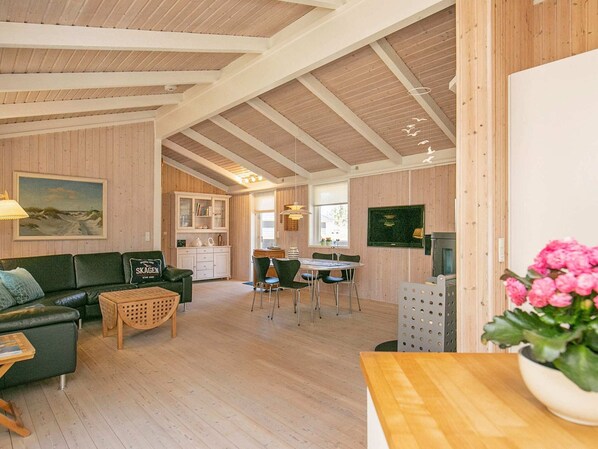 A cozy interior with a wooden ceiling, a dining area, and a living room with a sofa and a table. - Holiday Home in Strandby (Strandby)