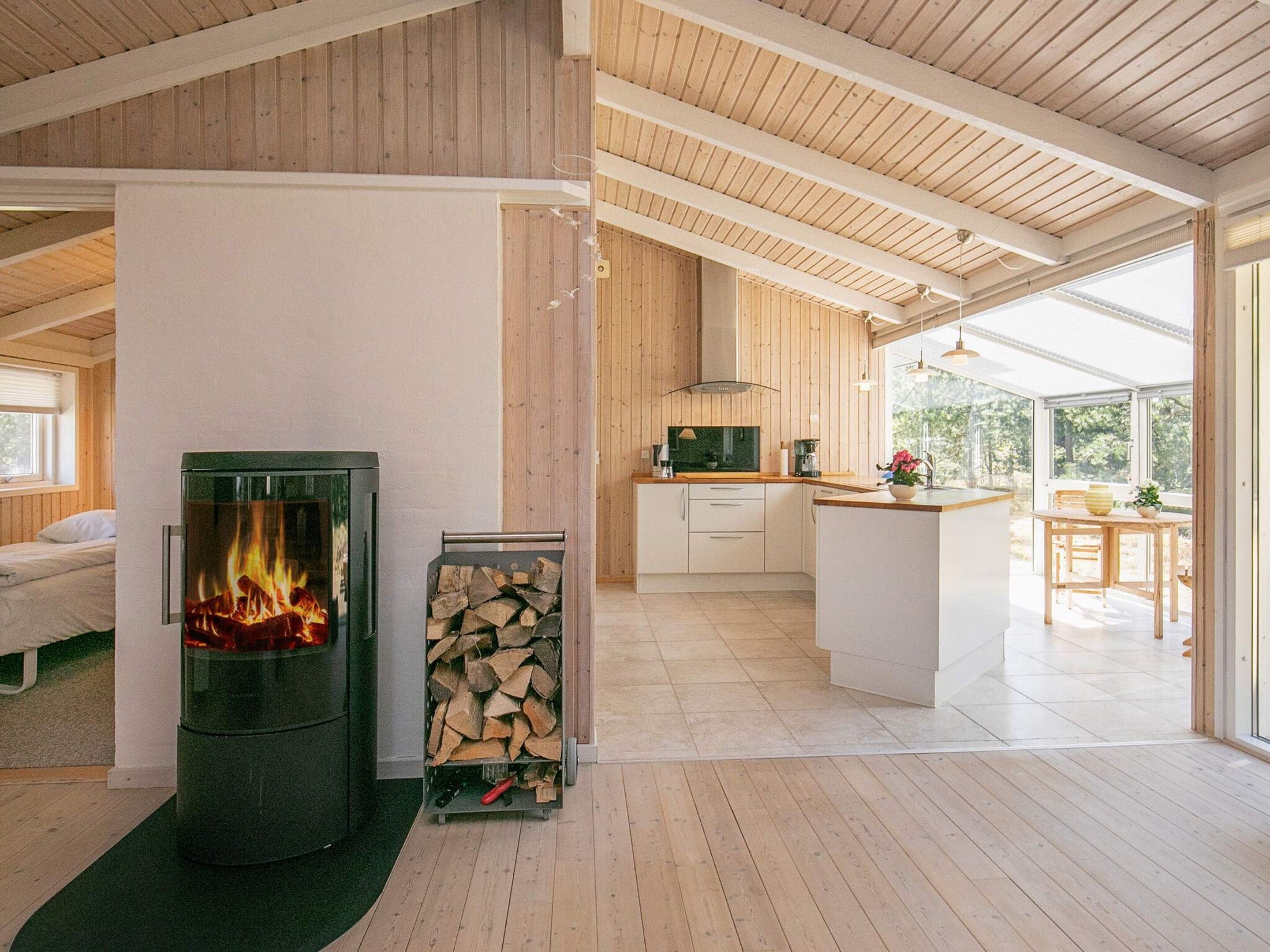 Ein modernes Interieur mit Kaminofen, Küchenbereich und Essplatz mit Blick.