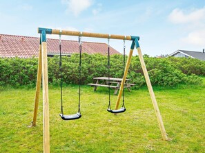 Relax in a serene backyard oasis with a sturdy swing set and picnic table.