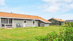 Una hilera de cabañas con un porche cubierto y un campo verde al frente.