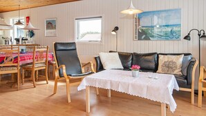Una habitación acogedora con techo de madera, una zona de comedor con mesa y sillas, un sofá y un cuadro en la pared.