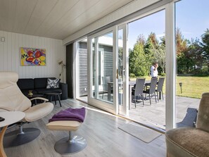 A modern living room with a sofa, a chair, and a dining area with a table and chairs. - Holiday Home in VÃ¦ggerlÃ¸se (Vaeggerlose)