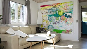 A modern living room with a beige sofa, a round coffee table, and a large abstract painting on the wall. - Holiday Home in VÃ¦ggerlÃ¸se (Vaeggerlose)