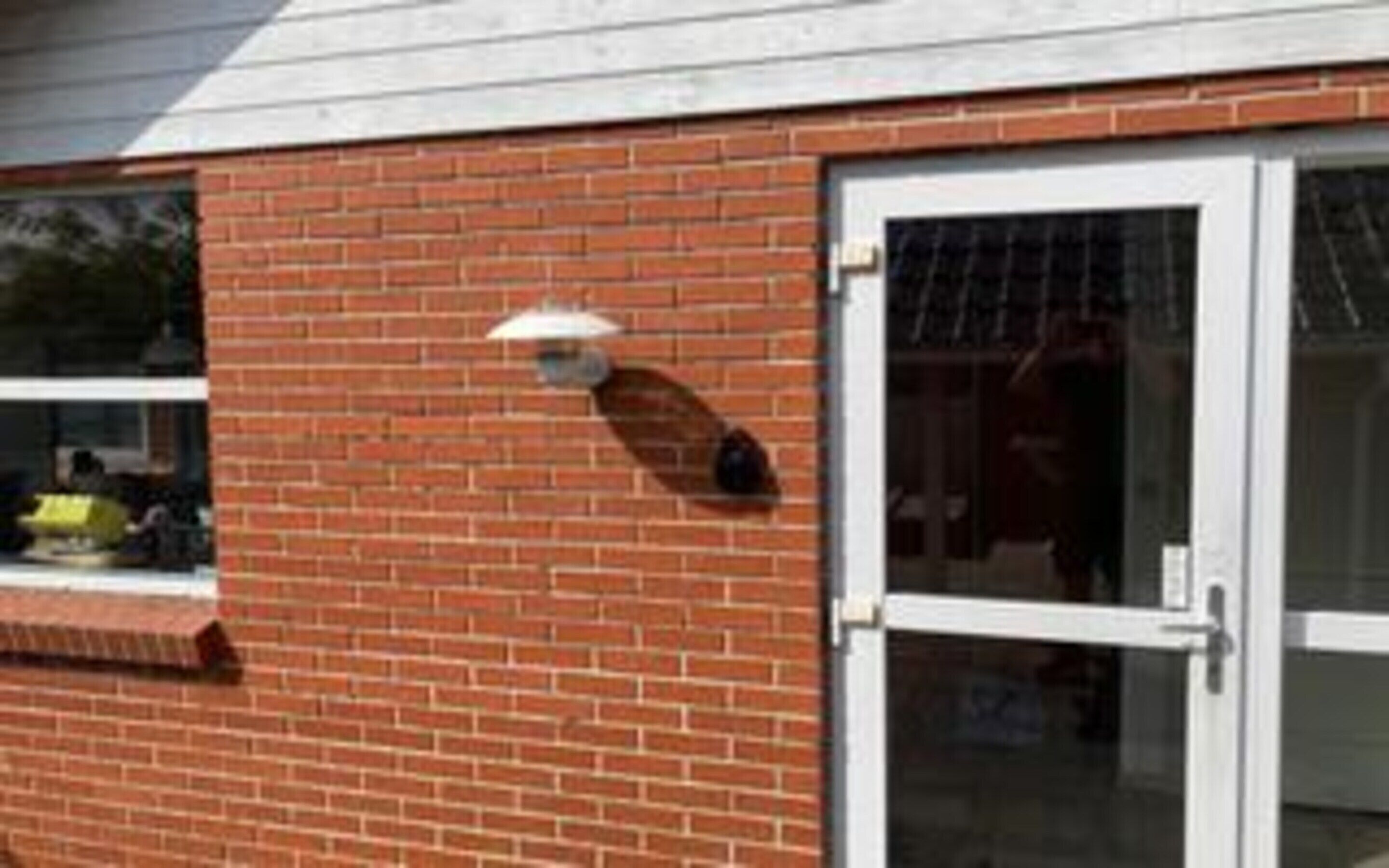 A brick building with a white door and a window with a white frame.