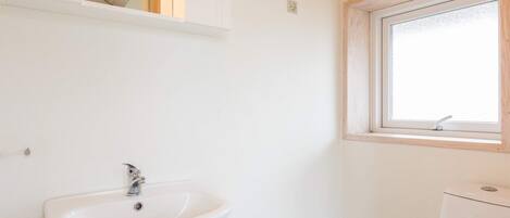 A bathroom with a white sink, a window, and a toilet.