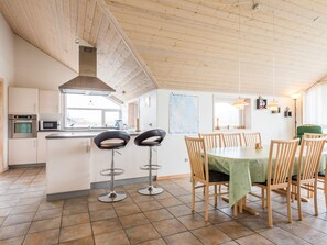 A modern kitchen with a dining area, featuring a large island, bar stools, and a dining table with chairs.