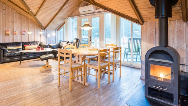A cozy cabin interior with a dining area, a sofa, and a wood-burning stove. - Charming Cottage Retreat-by Traum (Blavand)