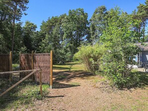 A fenced outdoor area with a gravel path leading to a swing set and a small building.