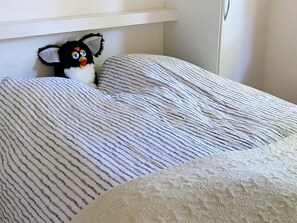 Un llit amb roba de llit ratllada i un peluix.