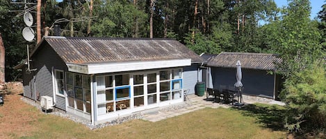 A small cabin with a metal roof, a large window, and a satellite dish.