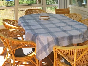 A table with a checkered tablecloth surrounded by wicker chairs. - 6 Person Holiday Home in Vaeggerlose (Vaeggerlose)