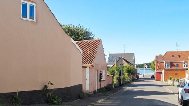 A residential street with houses, a parked car, and a clear sky.