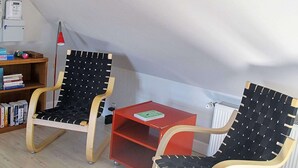 Two black and white woven chairs with wooden frames and a small red table with a book on it.