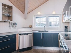 Een moderne keuken met een vaatwasser, een dubbele spoelbak en hangende lampen.