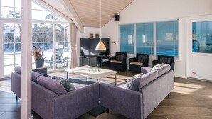 A modern living room with a sofa, chairs, a coffee table, and a TV. - 5 Star Holiday Home in Blavand (Blavand)