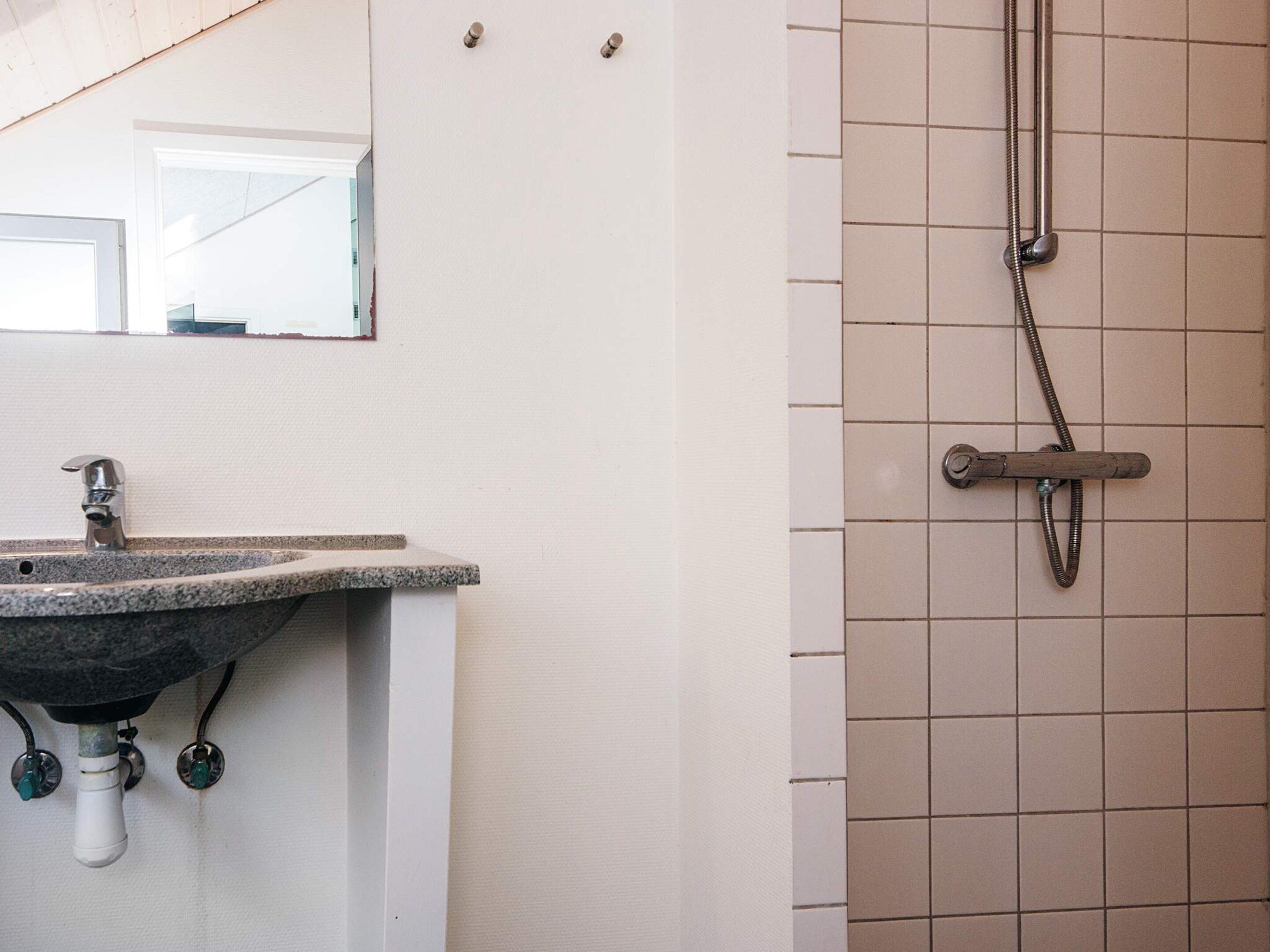 Une salle de bain avec un lavabo, un miroir et une douche.