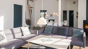 A modern living room with a large sofa, a coffee table, and a fireplace. - 5 Star Holiday Home in Blavand (Blavand)