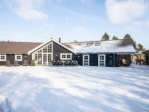 A building with a large patio area, a covered seating area, and a snow-covered ground.