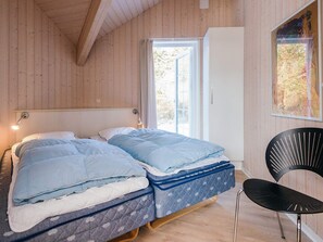Een slaapkamer met twee bedden, een raam en een stoel.