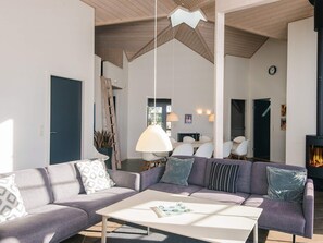 A modern living room with a sofa, coffee table, and a fireplace. - 5 Star Holiday Home in Blavand (Blavand)