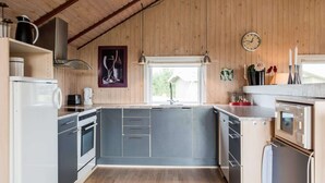 Een moderne keuken met houten wanden, een inbouwoven, een spoelbak en een klok aan de muur.