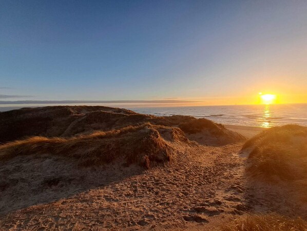 A beach with sand dunes and a sunset over the ocean. - 4 Star Holiday Home in Hvide Sande (Hvide Sande)