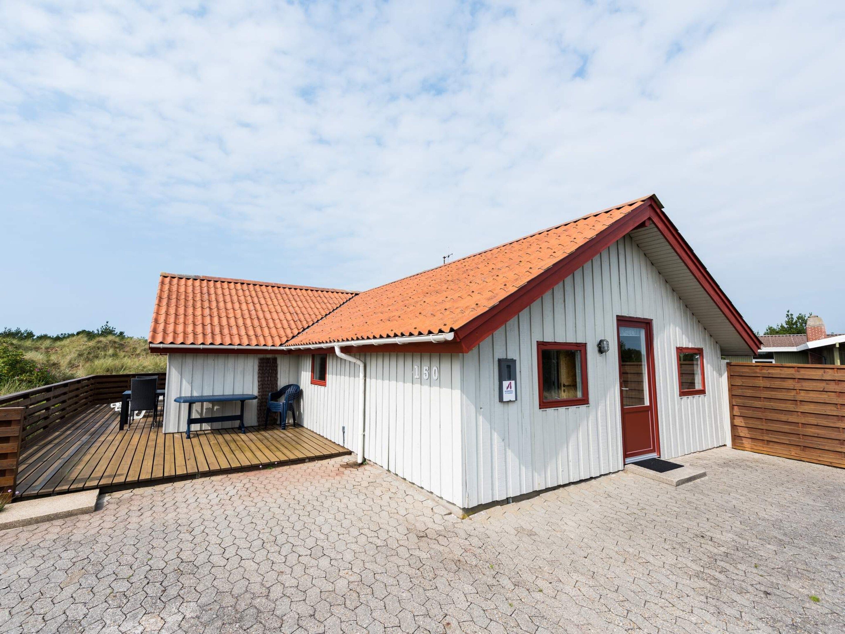 A small, single-story building with a red-tiled roof and a wooden deck.