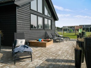 A patio with a sofa, a wooden table, and a lounge chair.