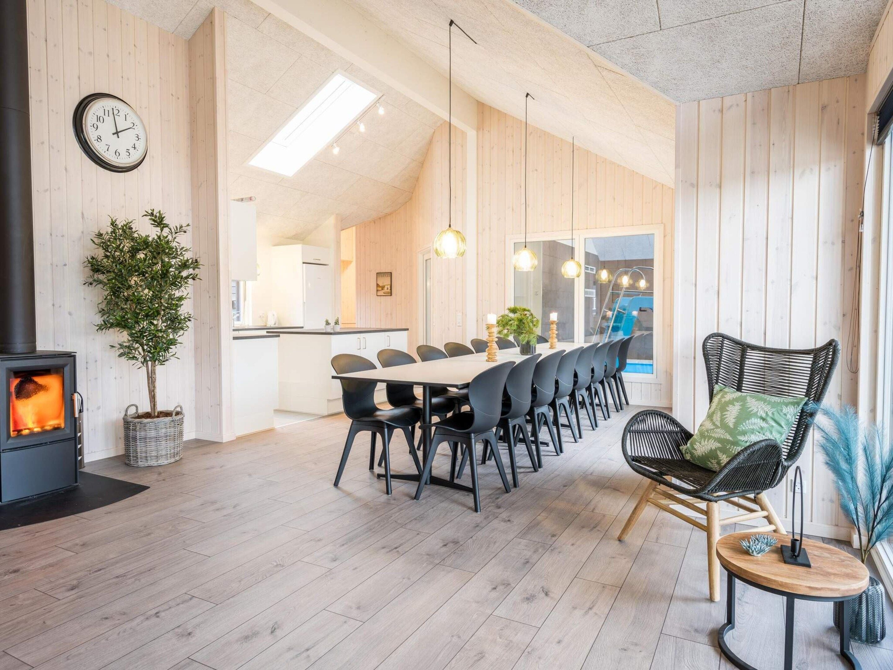 Un interior moderno con comedor, chimenea y vistas al exterior.
