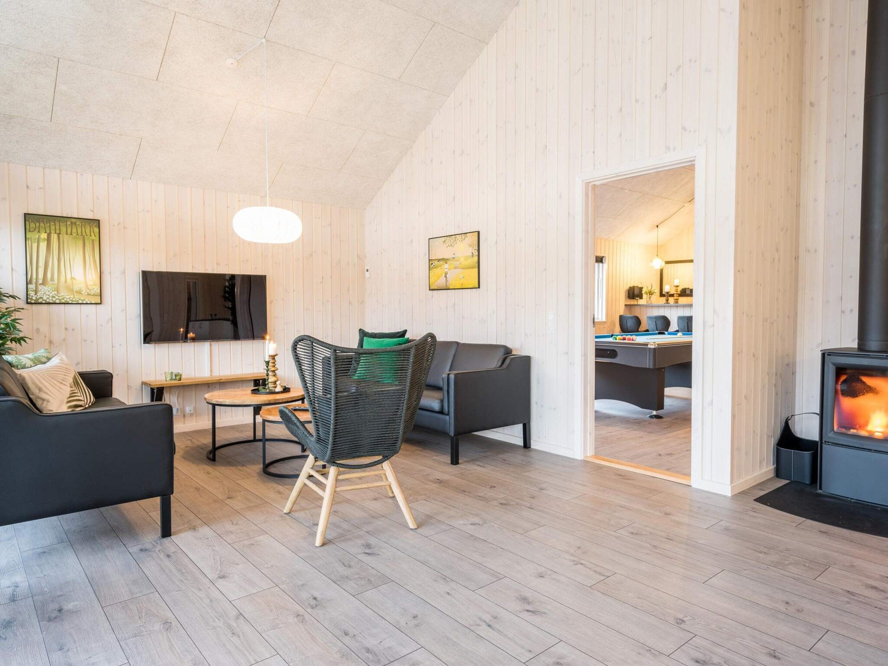 Un salon moderne avec une cheminée, un canapé, un fauteuil et un téléviseur.