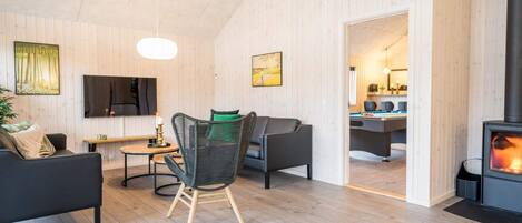 Un salon moderne avec une cheminée, un canapé, un fauteuil et un téléviseur.